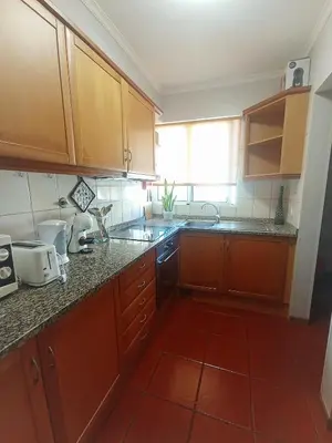 a kitchen with wooden cabinets and a red tile floor at Village Sea House - Porto Moniz in Porto Moniz