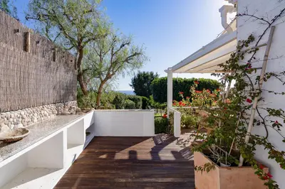 a garden with a stone wall and a pergola at Cliffside Boho Villa in Luz