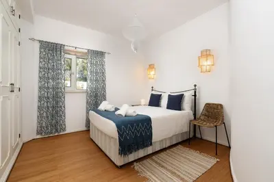 a white bedroom with a bed and a window at Cliffside Boho Villa in Luz