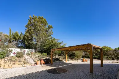 a wooden pavilion in a garden with potted plants at Cliffside Boho Villa in Luz