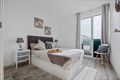 a white bedroom with a bed and a window at Apartamento Costa in Funchal