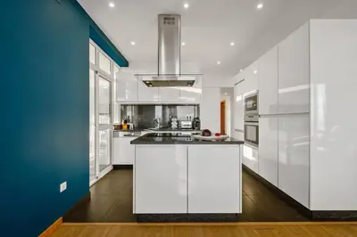 a kitchen with white cabinets and a blue wall at Apartamento Eden in Funchal
