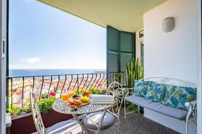 a balcony with a table and chairs and a view of the ocean at Apartamento Eden in Funchal