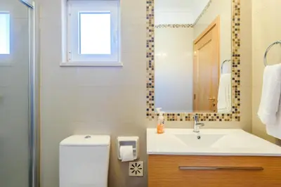 a bathroom with a sink and a toilet and a mirror at The White House in Lagos