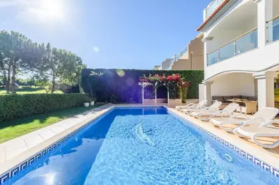 a swimming pool with lounge chairs next to a house at The White House in Lagos