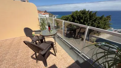 a balcony with a table and chairs and the ocean at Sunny Pearl Apartment in Caniço