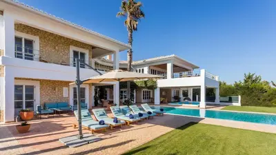 a villa with a swimming pool with chairs and an umbrella at Luxury Villa by the Sea with Ocean Views in Luz