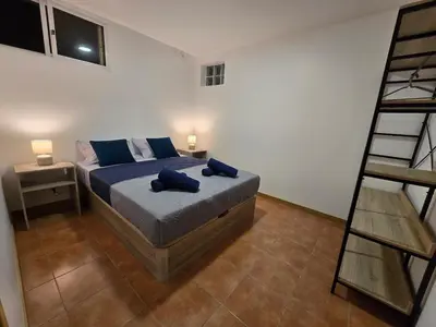 a bedroom with a bed with blue pillows and a ladder at Autonomia House I in Câmara de Lobos