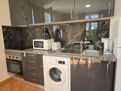 a kitchen with a washing machine and a microwave at Autonomia House I in Câmara de Lobos