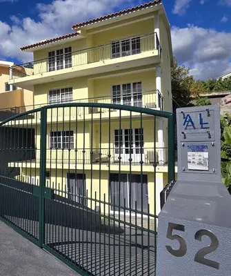 a yellow building with a sign in front of it at Autonomia House II in Câmara de Lobos