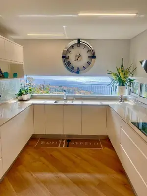 a large kitchen with a clock on the wall at Vila Da Luz Calheta in Estreito da Calheta