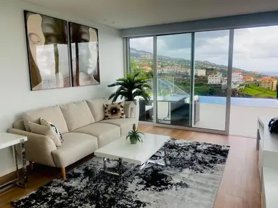 a living room with a couch and a large window at Vila Da Luz Calheta in Estreito da Calheta