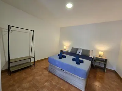 a bedroom with a bed with blue sheets and a mirror at Autonomia House III in Câmara de Lobos
