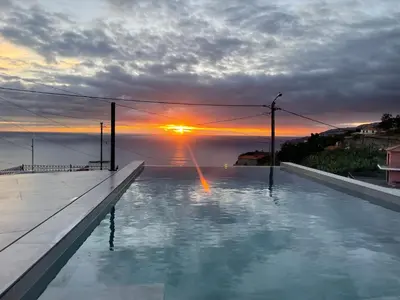 a swimming pool with a sunset in the background at Sun Temple by Madeira Holiday Rentals in Ribeira Brava