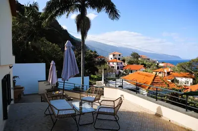 a patio with chairs and a table and umbrella at Casa Tio Albino I, By OP in Ponta Delgada