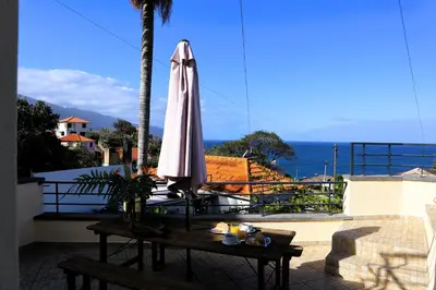 a white umbrella sitting on a table on a balcony at Casa Tio Albino I, By OP in Ponta Delgada