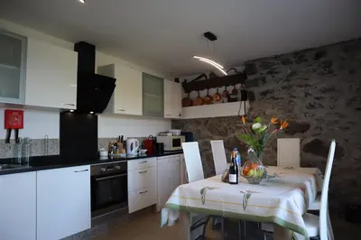 a kitchen with a table and a kitchen with white cabinets at Casa do Tio Albino II, By OP in Ponta Delgada
