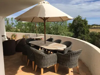a table and chairs with an umbrella on a balcony at Casa AncoraDouro in Lagos