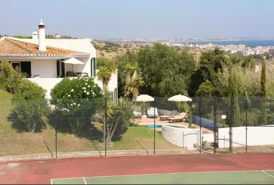 a house with a tennis court behind a fence at Casa AncoraDouro in Lagos