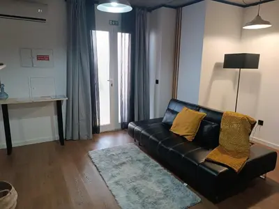 a living room with a black leather couch and a rug at Kings B&B Eiras in Caniço