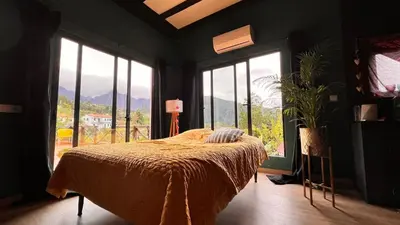 a bedroom with a bed in a room with windows at Quinta Vista para o Pico in Faial
