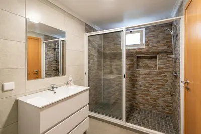 a bathroom with a sink and a shower with a glass door at Casa Branca, in the Heart of Arco da Calheta in Arco da Calheta