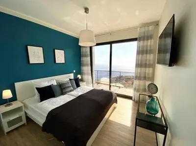 a bedroom with a large bed and a large window at Shangri Sol - Holiday house in Arco da Calheta