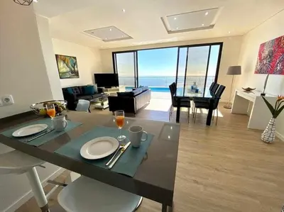 a living room with a dining table with a view of the ocean at Shangri Sol - Holiday house in Arco da Calheta