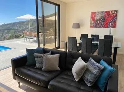 a living room with a black leather couch with pillows at Shangri Sol - Holiday house in Arco da Calheta