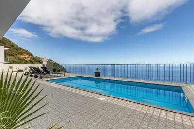 a swimming pool with a view of the ocean at Ocean and Palms in Arco da Calheta