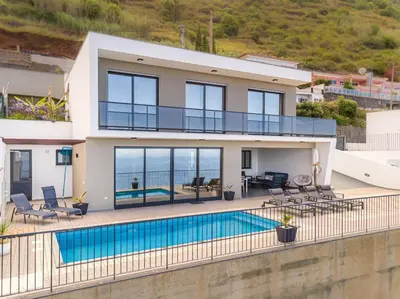 a villa with a swimming pool and a house at Ocean and Palms in Arco da Calheta
