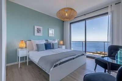 a bedroom with a large bed with a large window at Ocean and Palms in Arco da Calheta