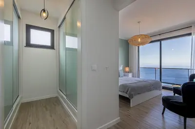 a bedroom with a bed and a view of the ocean at Ocean and Palms in Arco da Calheta