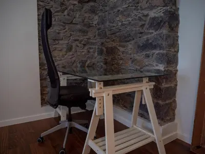a desk with a chair in front of a stone wall at Ocean's 13 in Ponta do Sol