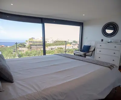 a bedroom with a large bed with a large window at Ocean's 13 in Ponta do Sol