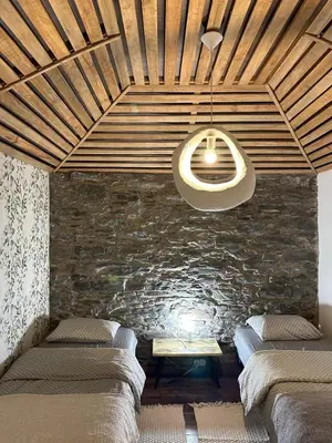 a room with three beds and a stone wall at Casa de basalto in Caniço