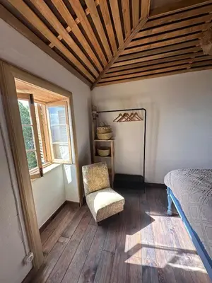 a bedroom with a bed and a chair and a window at Casa de basalto in Caniço