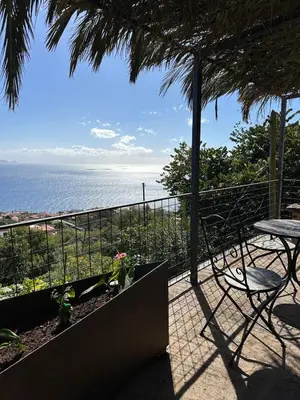 a balcony with a table and chairs and the ocean at Casa de basalto in Caniço