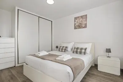 a white bedroom with a large white bed and two night stands at Seaside Charm II in Câmara de Lobos