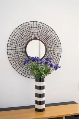 a round mirror in a black and white vase with purple flowers at Villa Carlota by Holiday Rental Madeira in Caniço