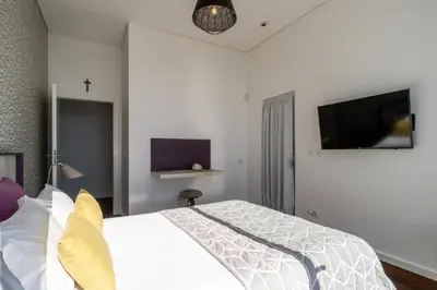 a bedroom with a white bed and a tv at Villa Carlota by Holiday Rental Madeira in Caniço