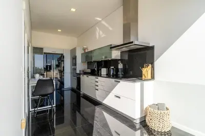 a kitchen with white cabinets and a black counter top at Villa Carlota by Holiday Rental Madeira in Caniço