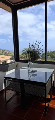 a table with a vase on it in front of a window at Sally's Loft - Penthouse - Honeymoon suite in Ponta do Sol