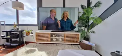 a living room with a tv with a man and a woman at Sally's Loft - Penthouse - Honeymoon suite in Ponta do Sol