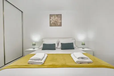 a white bedroom with a large bed with towels on it at Seaside Charm I in Câmara de Lobos