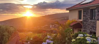 a sunset over a house with a garden at Recanto das Florenças - Casa 3 in Arco da Calheta