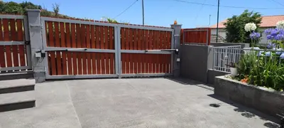 a red fence with a gate and some flowers at Recanto das Florenças - Casa 3 in Arco da Calheta