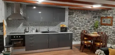 a kitchen with gray cabinets and a stone wall at Recanto das Florenças - Casa 3 in Arco da Calheta