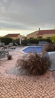 a swimming pool with benches next to a building at Modern house with private Pool in Sagres
