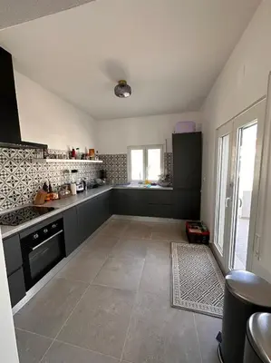 a large kitchen with black and white appliances at Modern house with private Pool in Sagres